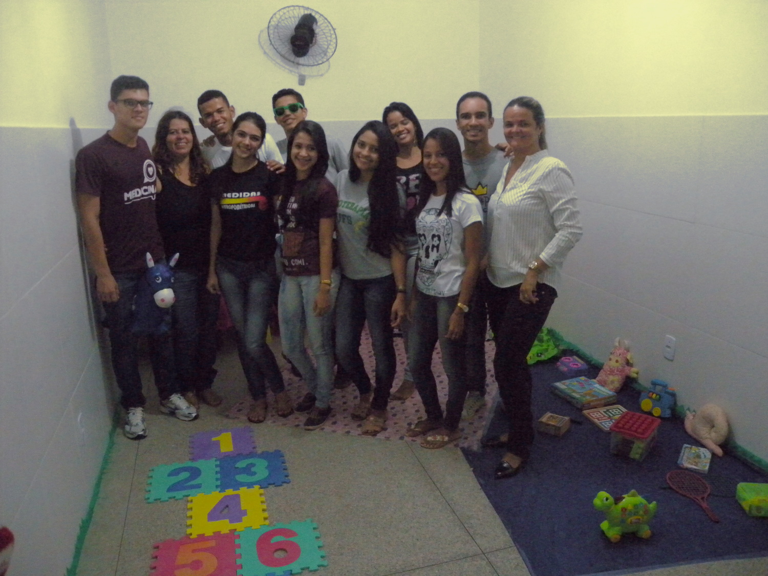 Alunos na Sala de Acolhimento às crianças na UBS Maria do Carmo com a Assistente Social Rosana Alves (de camisa branca no lado direito da foto)